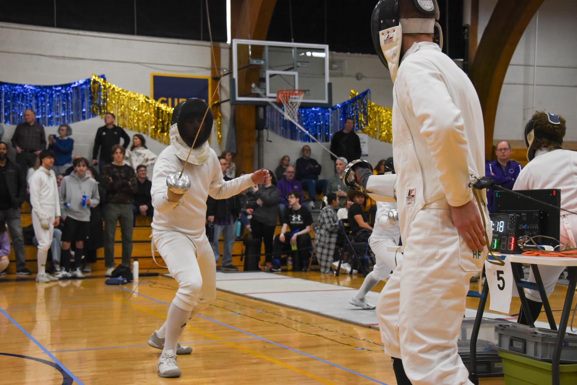 EN GARDE. Senior Maik Nguyen gets into position to fence his first round in Junior Mens Épée in the large gym as his friends watches from the sidelines.