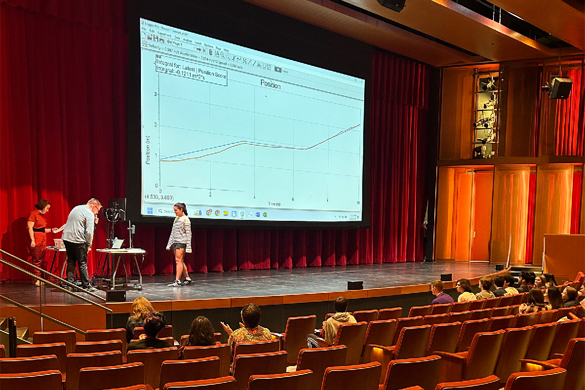 WALK THE LINE. Senior Audrey Senaratna gets ready for her second try at mtaching the graph. The crowd laughs as Upper School science teacher Scot Hovan jokes about a sibling rivalry between Senaratna and her younger brother and 2024 freshman graph matching champion Isaak Senaratna.