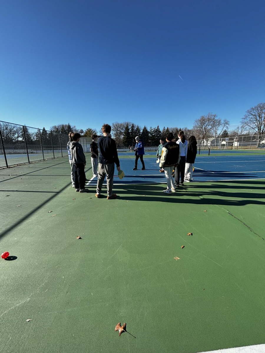 BACK+OUTDOORS.+The+pickleball+club+stands+outside+in+a+circle+as+they+play+Spud%2C+a+strategic+tag+game+played+with+pickleball+balls+and+paddle%2C+with+the+entire+club.+Club+adviser+Ben+Bollinger+Danielson+said%2C+%E2%80%9CI+love+any+opportunity+to+get+students+playing+games.+I+like+being+outside+and+Pickleball+is+just+a+great+activity.%E2%80%9D