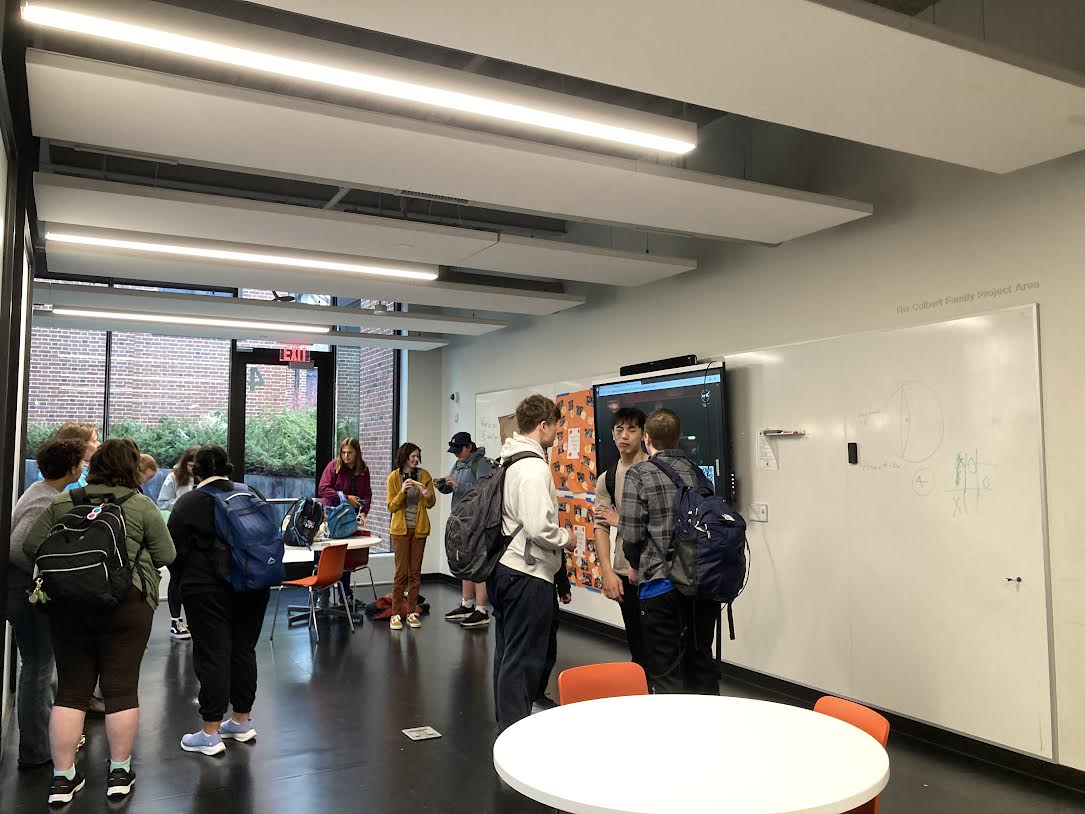 VIEWING PARTY. Students gather around a screen livestreaming the event.