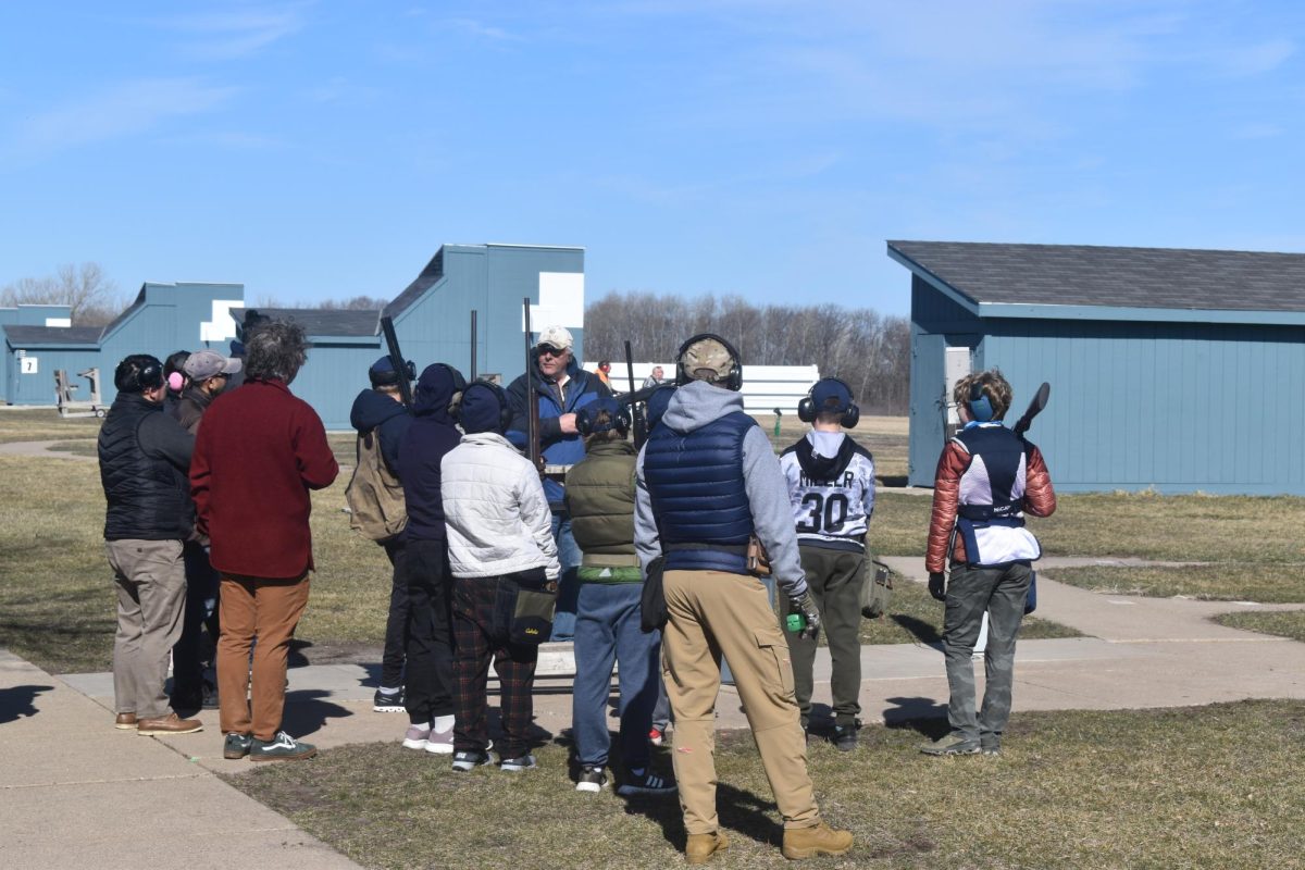 GATHERING AROUND. Beginner shooters convene together for an intro on trap shooting, with their parents listening in from behind.