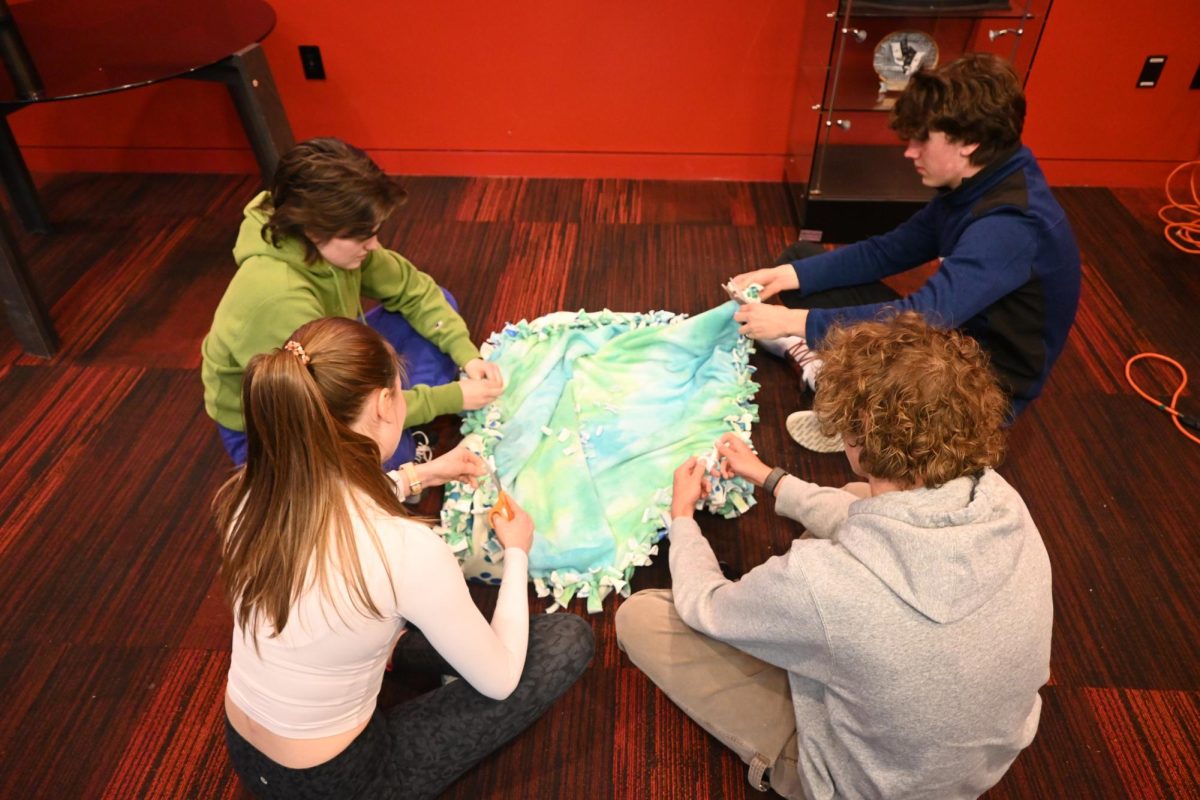 TYING IT ALL TOGETHER. Senior Bridget Keel, juniors Taylor Barkwell and Thomas Kovarik and sophomore Elliot Sjaastad complete a blanket.