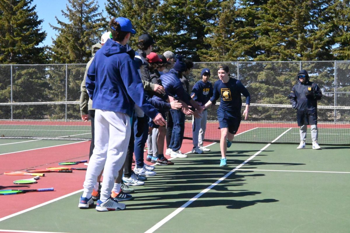 DOWN THE FIVE LANE. Junior David Schumacher runs down the court while high-fiving his teammates in the line. "I think that these matches really proved that we can hang with the good double A teams and it's just a matter of rising to the level from an emotional standpoint," said Schumacher.