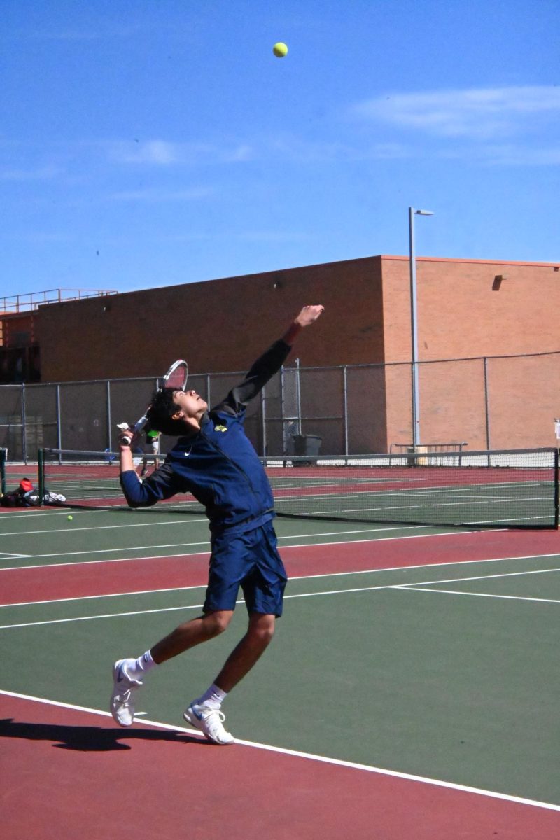 UP IN THE SKY. Senior Baasit Mahmood throws the ball into the air to serve to the other team. Mahmood is a singles player, and there were three other Spartans playing singles during the second match.