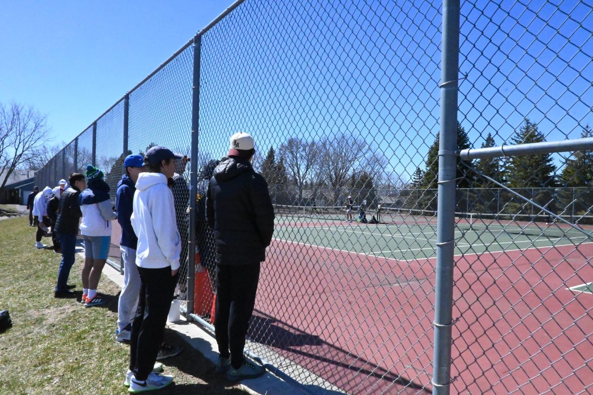 PEERING IN. Athletes look through the fence into the courts to cheer on their fellow Spartans. Junior David Schumacher said, I was really happy to get back in the matches. I think that the way this team deals with competition is really positive and fun, so I was really happy to get back into that rhythm.”