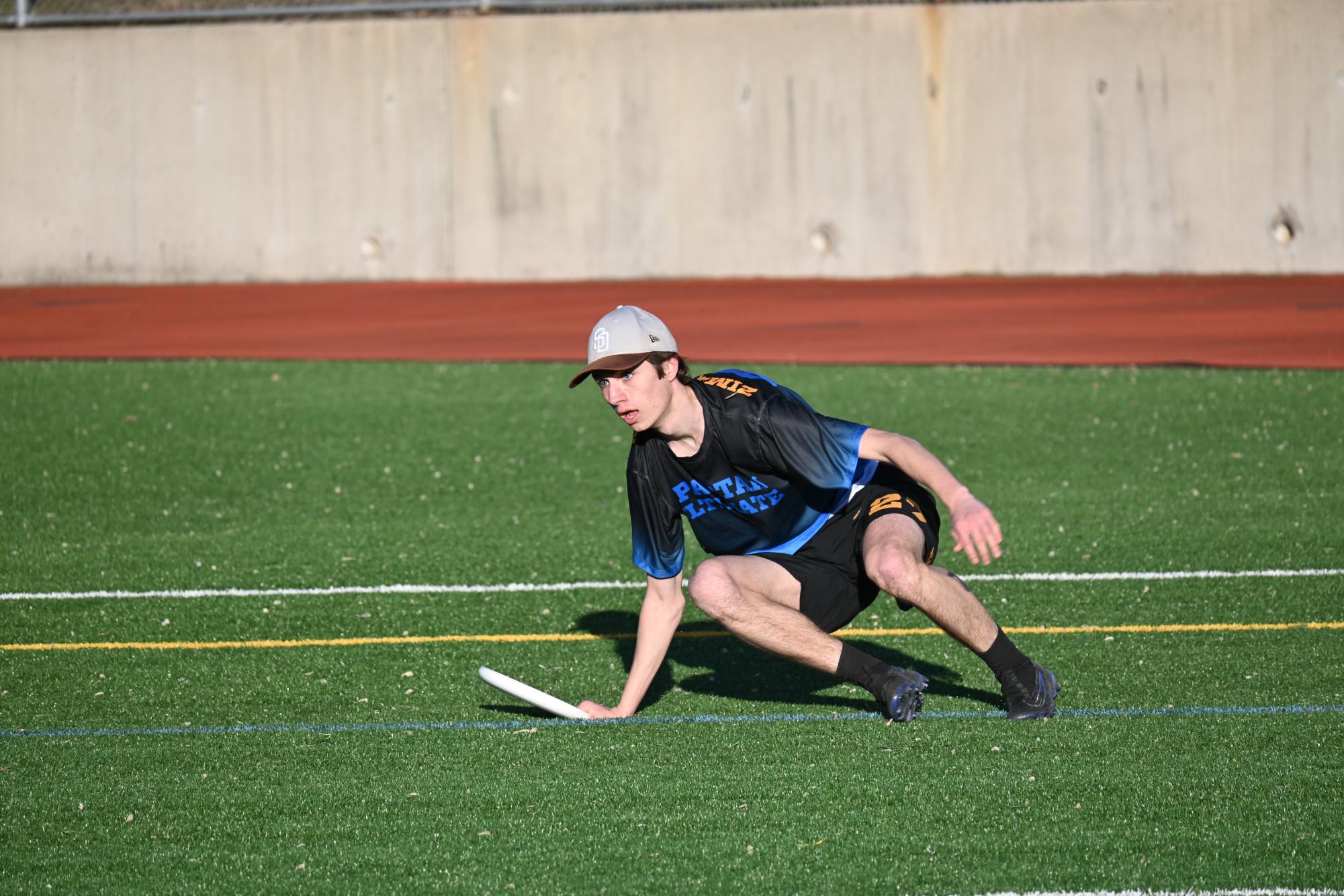 LOCKED IN. Senior Theo Zimmerman, a more experienced player, springs up off the grass with the frisbee in hand after taking a fall.
