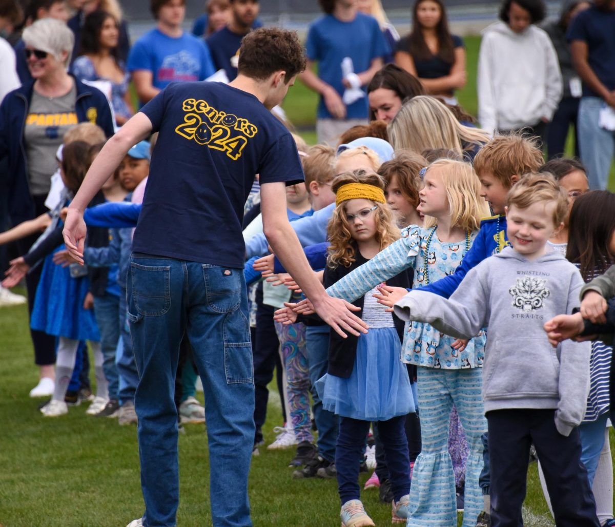 HIGH-FIVE. Senior William Richardson goes down the line of kindergarteners, giving them high-fives. At the end of the line, each senior was given a handkerchief to commemorate the day.