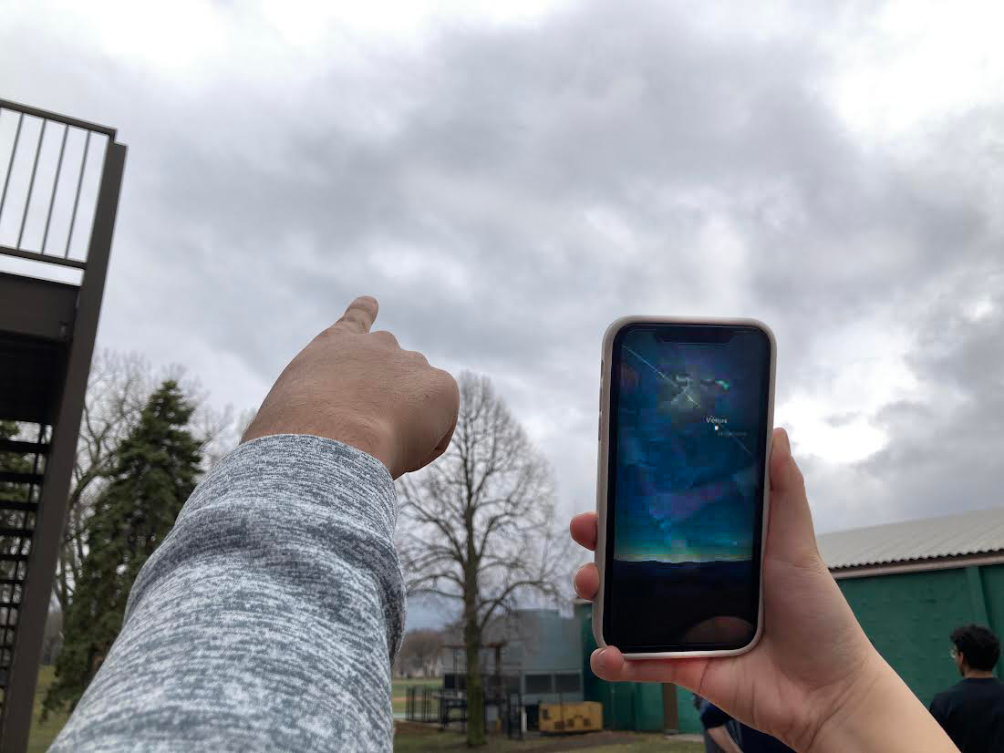 FAR OUT. Senior Oliver Zhu holds up an app displaying the planets should have been visible while sophomore Zain Kizilbash tracks where the sun would be.