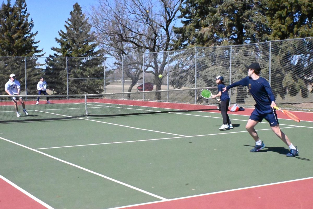 POWERING UP. Freshman Gavin Leuthold gets ready to swing his tennis racket to hit the ball coming from the Mahtomedi Zephyrs. This was the Spartans second match of the day, and the doubles team composed of Leuthold and seventh-grader Caleb Colton were playing their match on the furthest left side of the court.