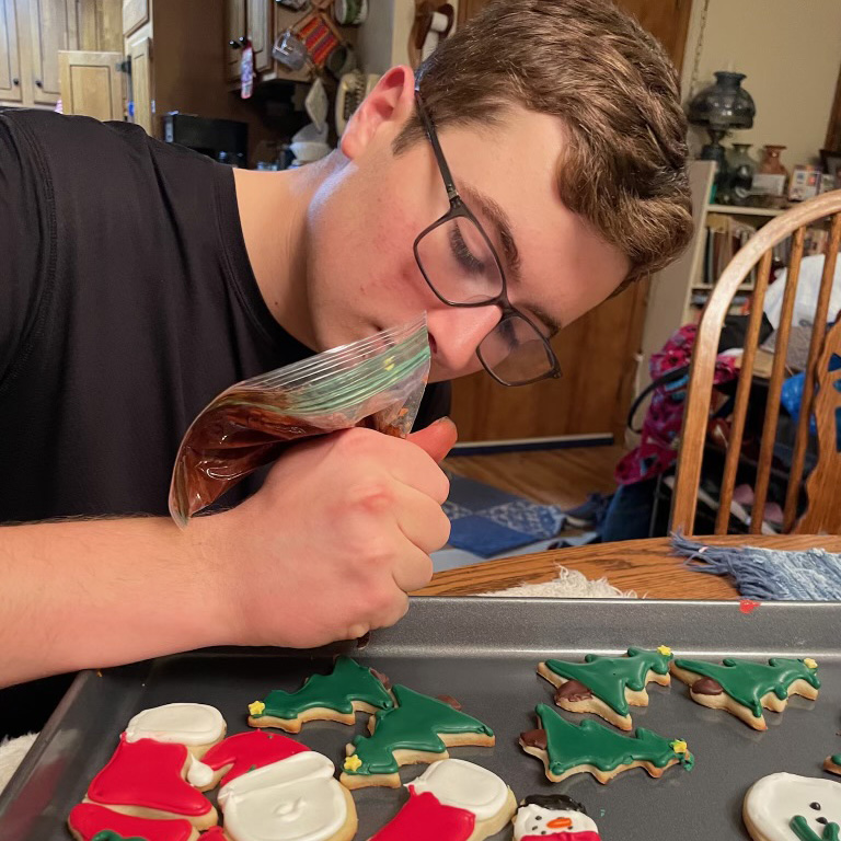 COOKIE LEGACY. Senior Andrew Drake bakes Christmas-themed cookies and frosts them at the dining table. Inspired by his grandmother, Drake has been baking for years. My grandma on my dads side does bake, so part of my inspiration came from her. We used to call her ‘Cookie Grandma’ because shed always have cookies for us and we came to visit, Drake said. (Submitted photo by Andrew Drake)