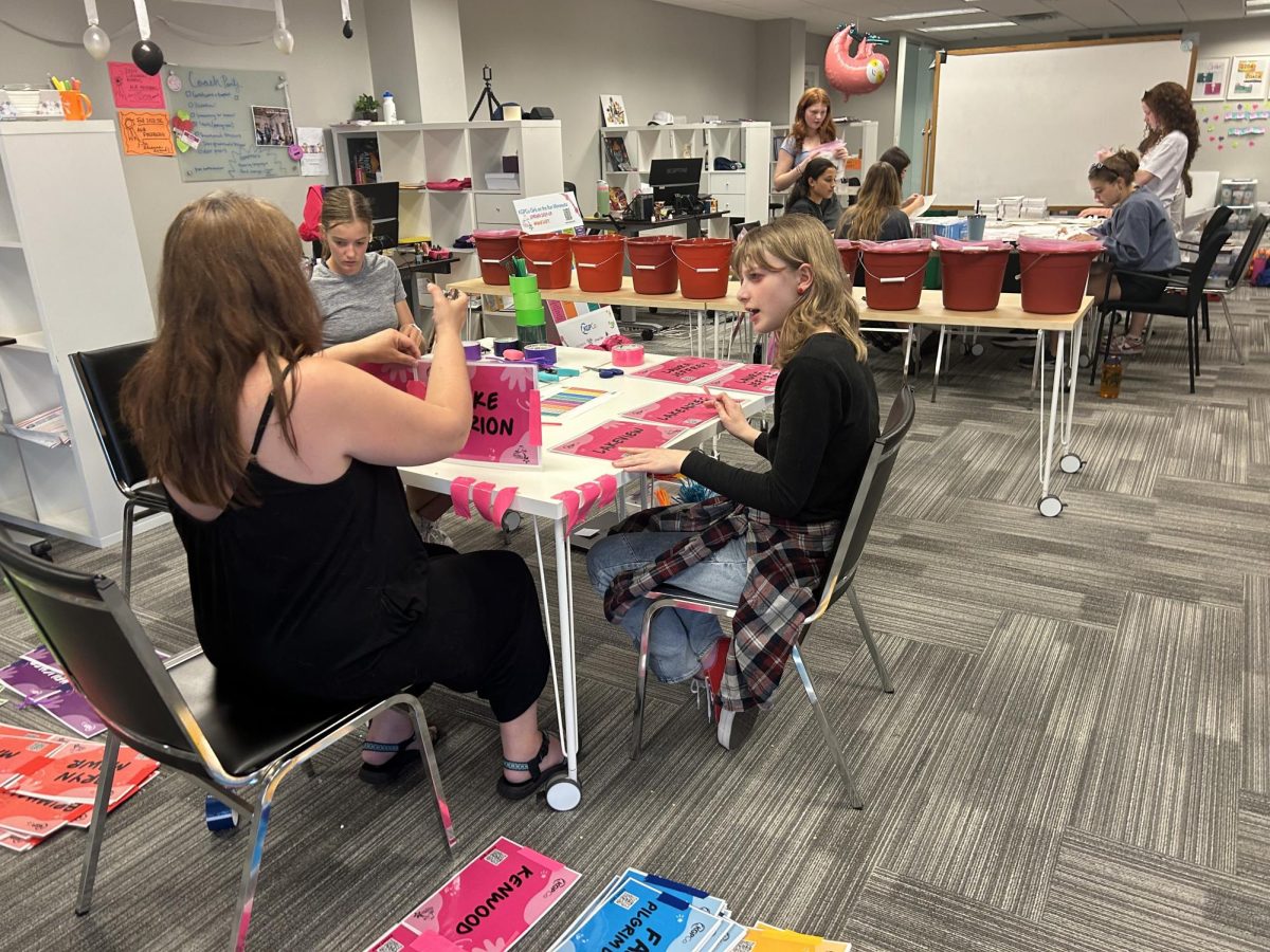 EMPOWERING TOGETHER. Freshman Tallulah Dogwell and Via Campbell as well as HerSpace advisor Kathryn Campbell worked on putting together school signs for runners.