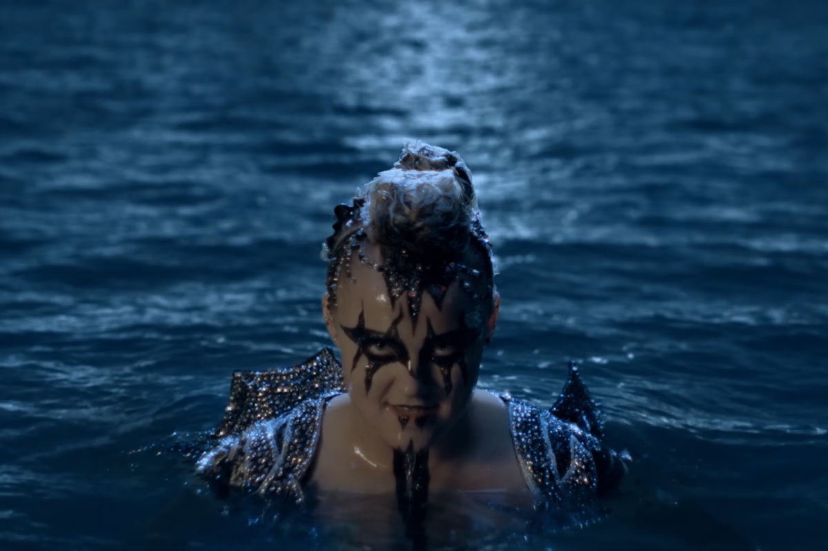 KARMA. JoJo Siwa emerges from an ocean in her infamous black face paint and sparkly body suit.  The music videos vivid and animated visuals keep up with the fast-paced and dramatic song. (Screen capture from “JoJo Siwa - Karma Official Video” by JoJo Siwa on YouTube.)
