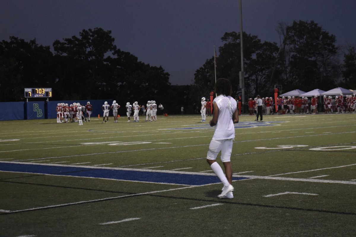 TEAMWORK. Wolfpack player walks towards his team on the sideline to support their teammates on the field.
