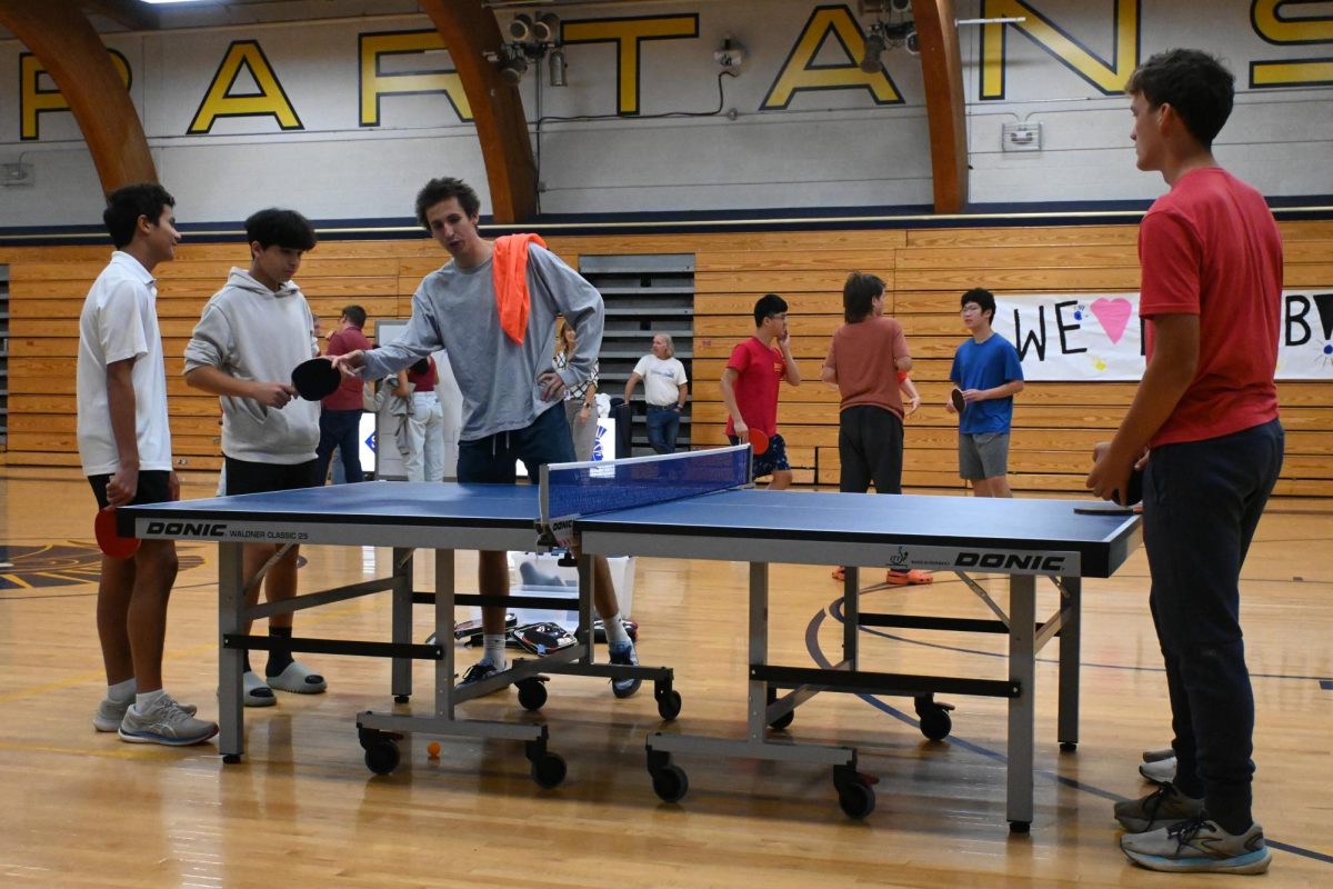 GAME RULES. SAC referee Liam Sullivan explains the ping pong rules to participants as they prepare for their first-round match.