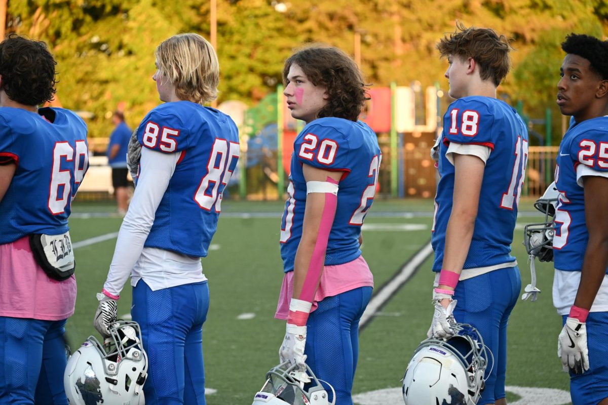 ANTHEM. Sauer (center) and teammates face the American flag with his hand on his heart while the national anthem plays.