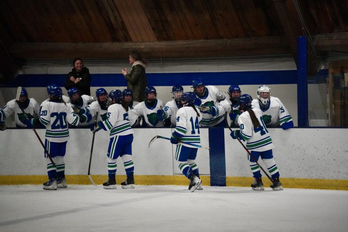 ENERGY BEHIND THE ICE. Blake players high-five their teammates after a sweet goal by SPA player Ella Bond.