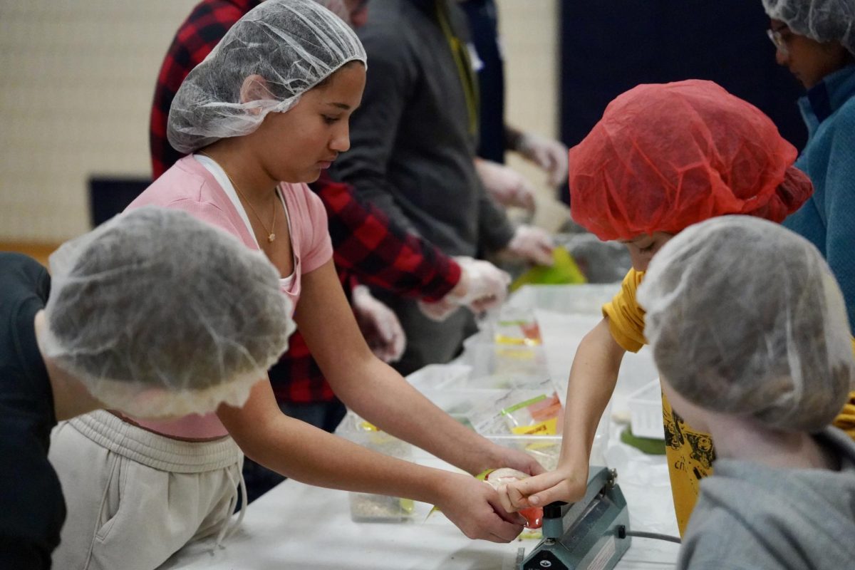 SEALING UP. Students take turns sealing bags and patiently waiting to box the meals up.