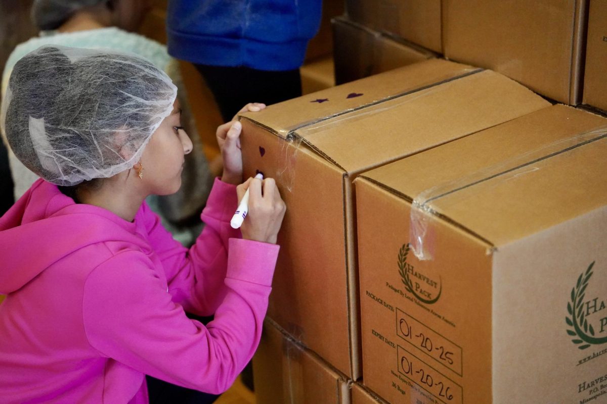 TOUCH OF LOVE. Student from the Lower School adds a touch of love to some packages.