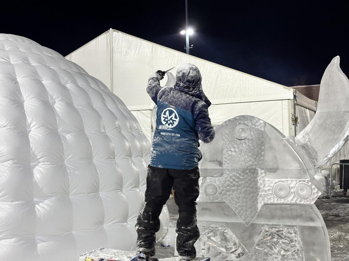 REFINE. An event staff is adding final details to an ice sculpture. The sculpture is of a viking helmet.