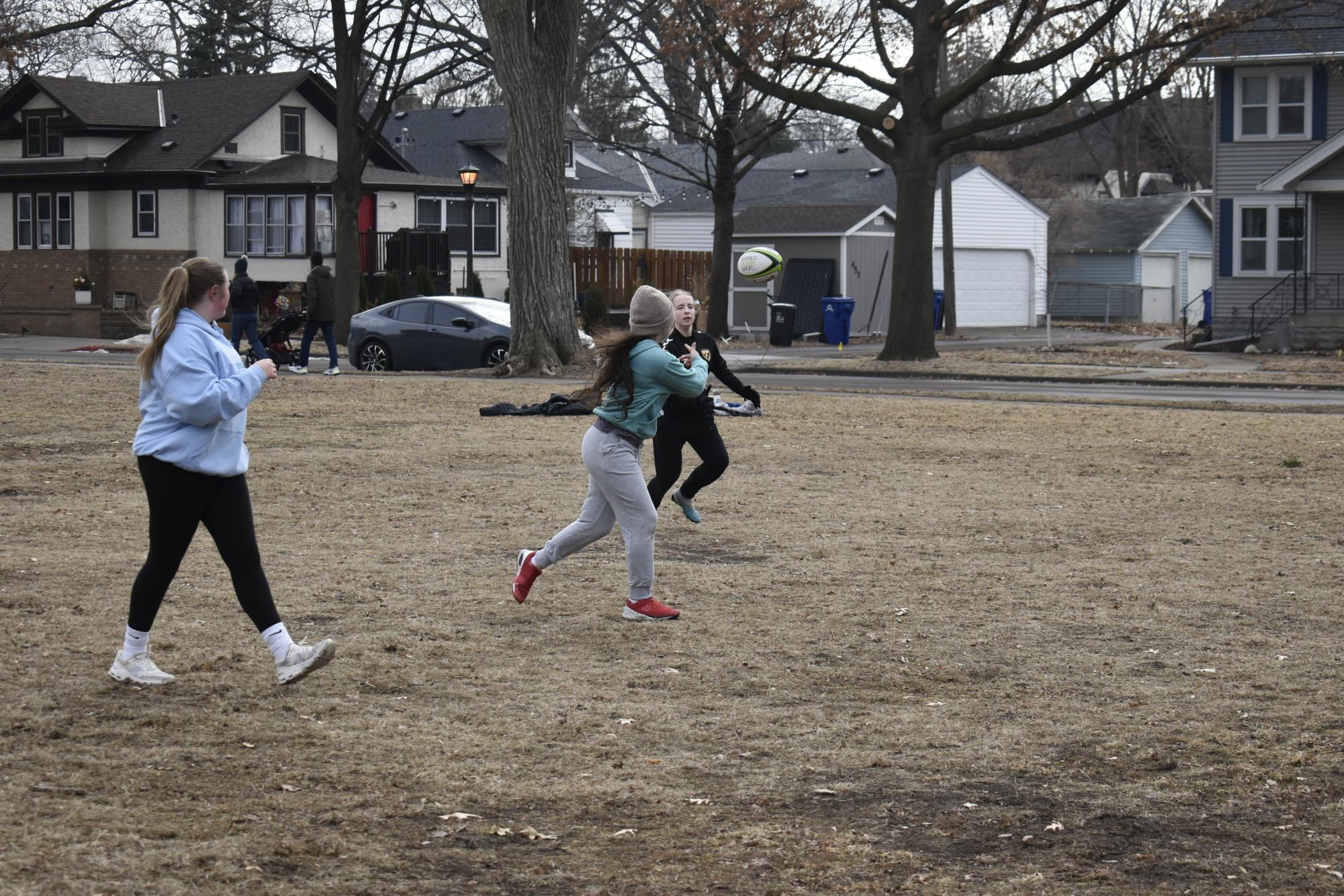 STEADY START. Sophomore Yasmin Khan throws a rugby ball to ninth-grader Eva Burns at the first girls rugby prac tice Feb. 1.