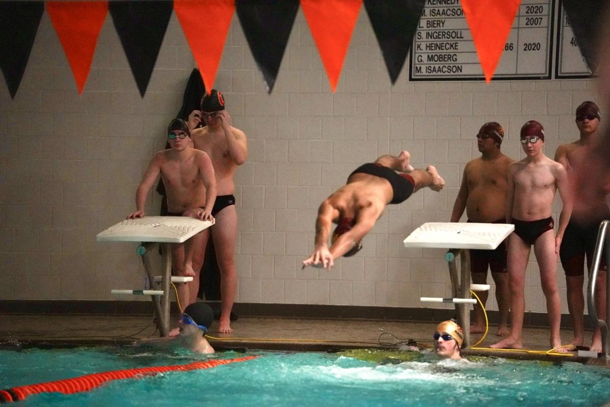 ABOVE THE SURFACE. During a relay, a Trojan swimmer dives into the water to start his portion of the race. 
