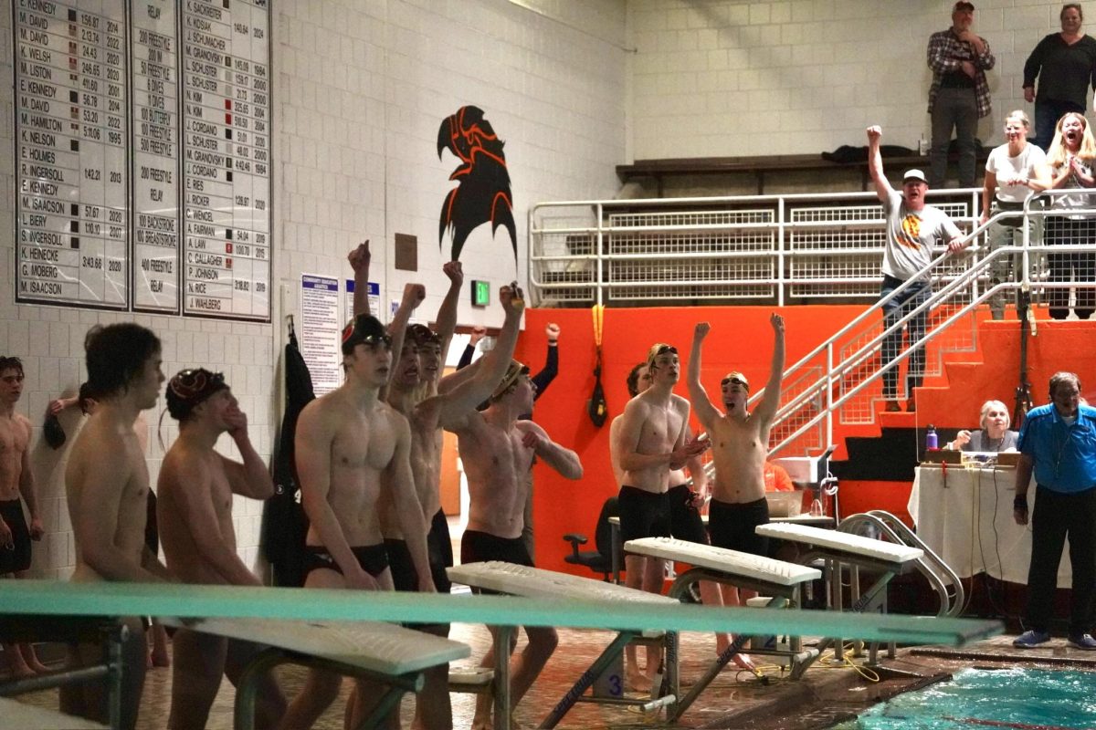 ANTICIPATION. Trojan swimmers wait to see the results of the meet. Some fans are already cheering.