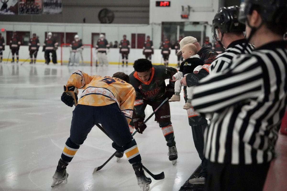 PUCK DROP. Captains from each team meet at center ice while Sawyer and her family drop the puck to mark the start of the game.