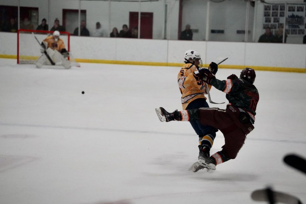 MID-AIR COLISSION. Sophomore Adem Rivers pushes a Johnson player off him in order to get to the puck.
