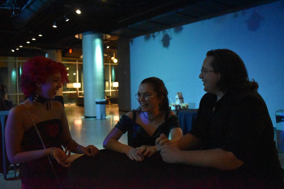 CATCHING UP. Juniors Sam Ray, Elzie Bieganek and Bieganek's guest from another school chat and catch up at a standing table near the entrance. 