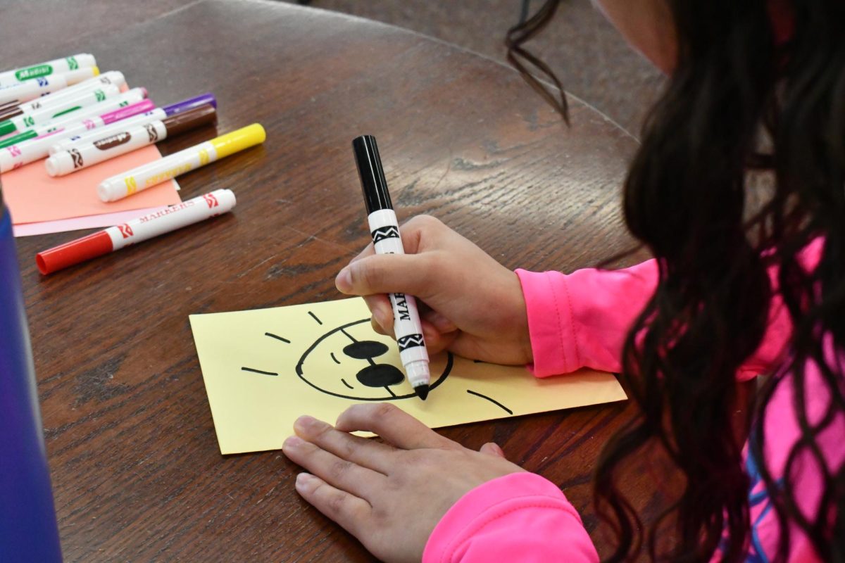 SUN IS SHINING. For Cards for Hospitalized Kids, senior Julia Taylor draws a happy sun with shades on the cover of her card.