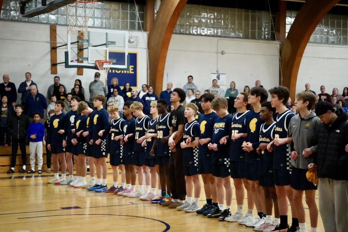 FAMILY. Boys basketball lines up before the game during the national anthem. They interlink arms to show camaraderie and teamwork.  
