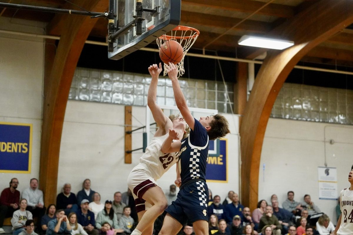 LAYUP. Sophomore Miles Vogenthaler makes a layup while being defended. 