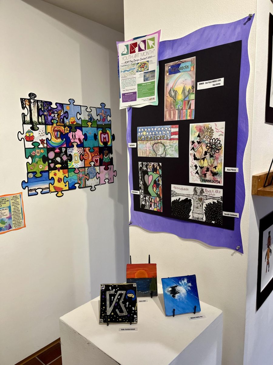 COMMUNITY DISPLAY. One corner of the room fosters community and variety with just a few artworks, such as the “Community Arts Special Interest Club Collaborative Puzzle,” which exhibits the club’s values of community and its sources of joy. 