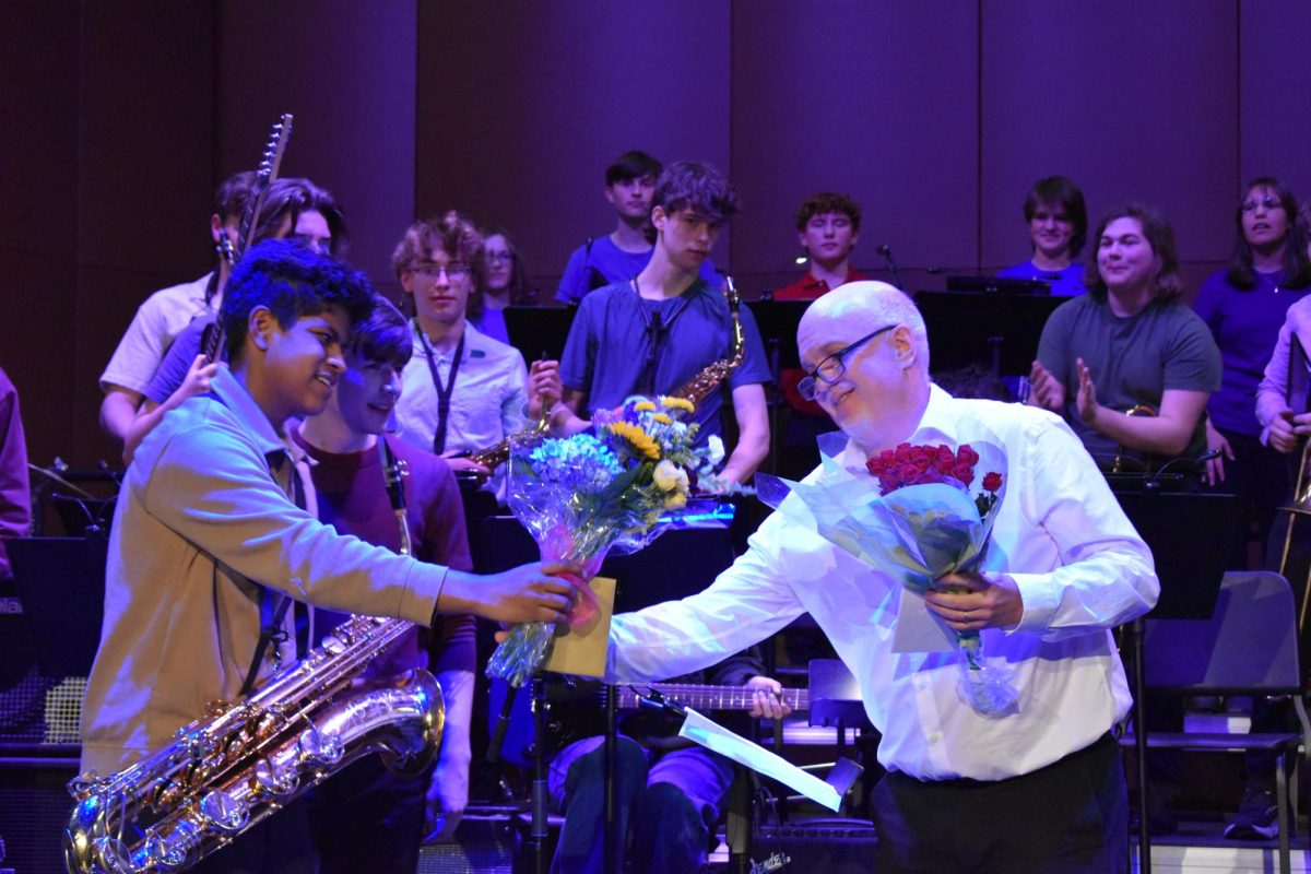 GIVE HIM HIS FLOWERS. Junior Juan Miguel Adams hands Director of Jazz Band Randy Reid bouquets of flowers. This gesture was to appreciate Reid for all he has done for the program as he is retiring this  year.