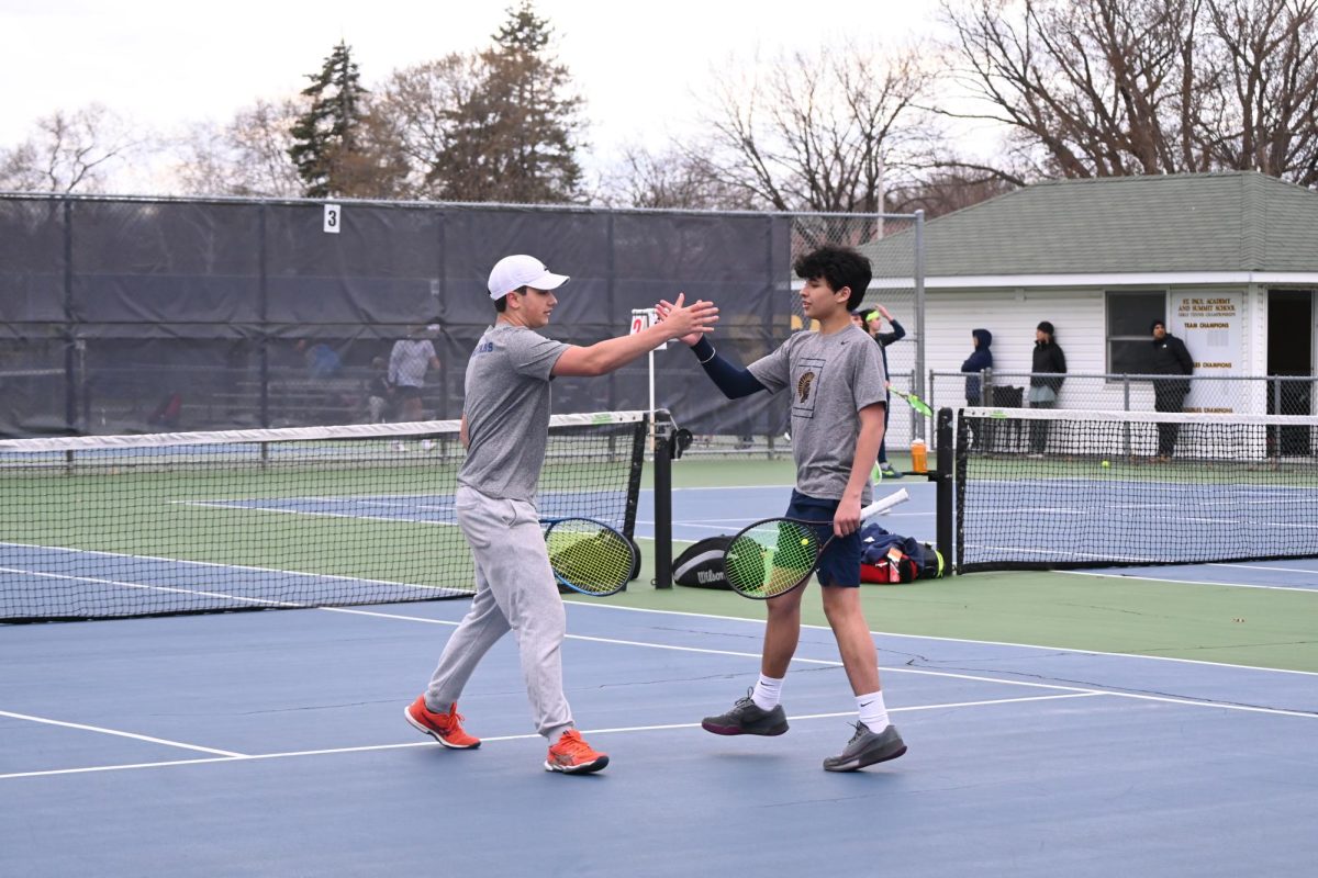 HIGH-FIVES. Captain Ben Macedo and freshmen Luca Kempcke hype each other up after a well-won point. Against Orono, all of the doubles players won, whereas all the singles lost, resulting in a 3-4 loss. “It was the same last year too,” said sophomore Gavin Leuthold.
