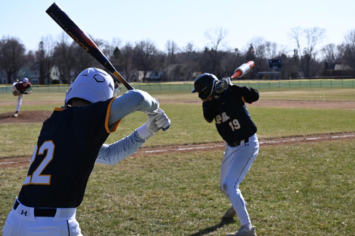 SWINGING SIMULTANEOUSLY. Senior Liam Huddleston and eight-grader Quinn Wall warm up.