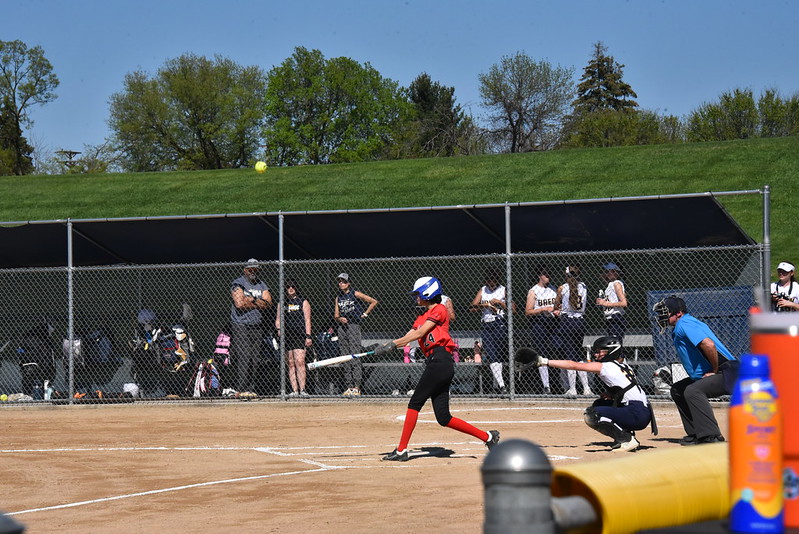 SWINGING AWAY: Redhawks batter swings a great ball. Breck catcher prepares to receive a ball, and the Mustangs’ other players and coach watch through the fence of their dugout. The batter then turned to run for first base.  
