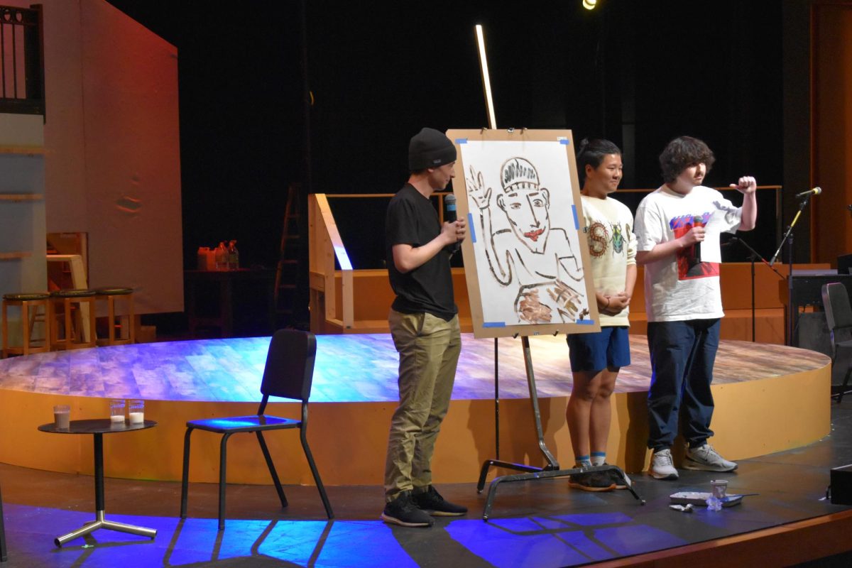 Talented Trio: juniors Roman Farley and Johann DeVriese entertain the crowd with a short podcast while junior Ethan He draws up a caricature of Farley.