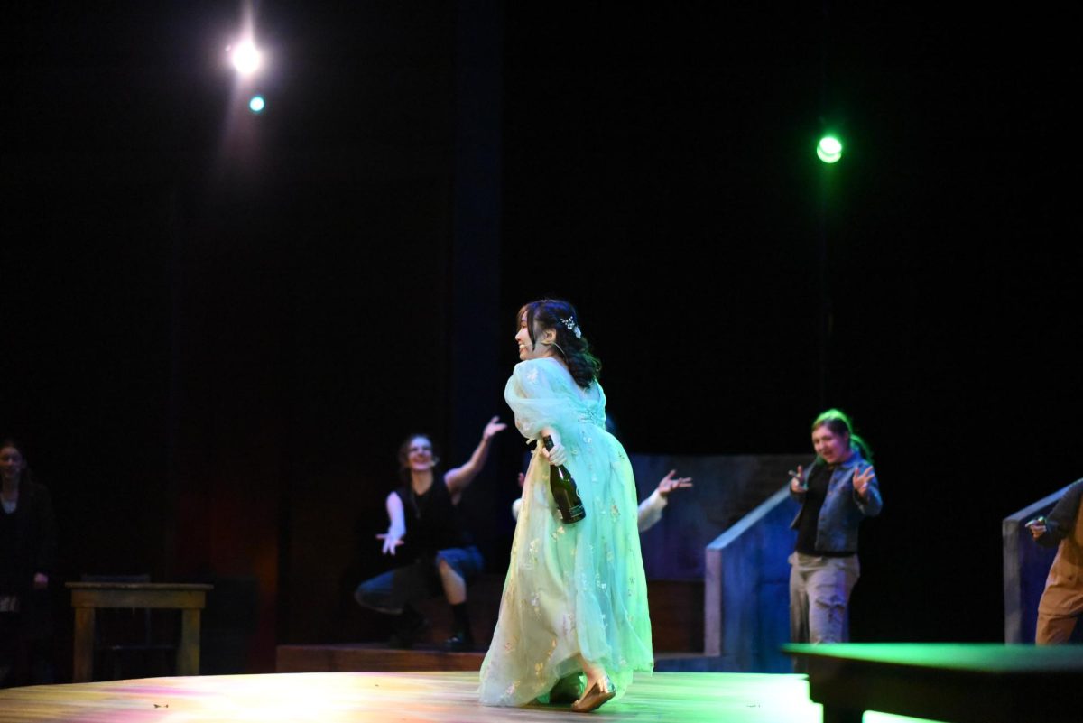 LIVIN' IT UP ON TOP. Persephone (Ellie Putaski) celebrates with the cast on the Earth's surface. 