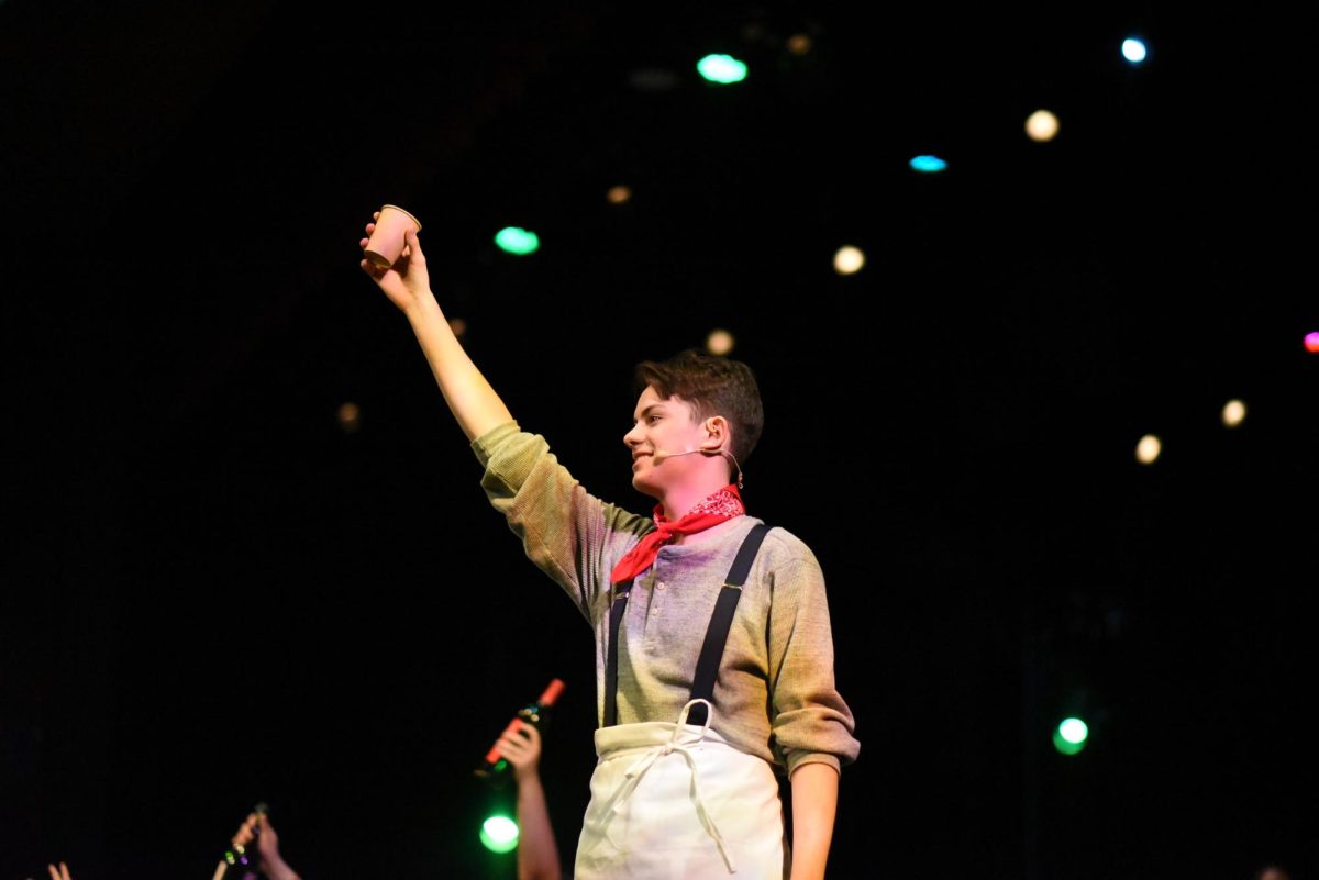 CHEERS. In "Livin' it Up on Top," Orpheus (Coda Wilson) holds his cup up to the audience. 
