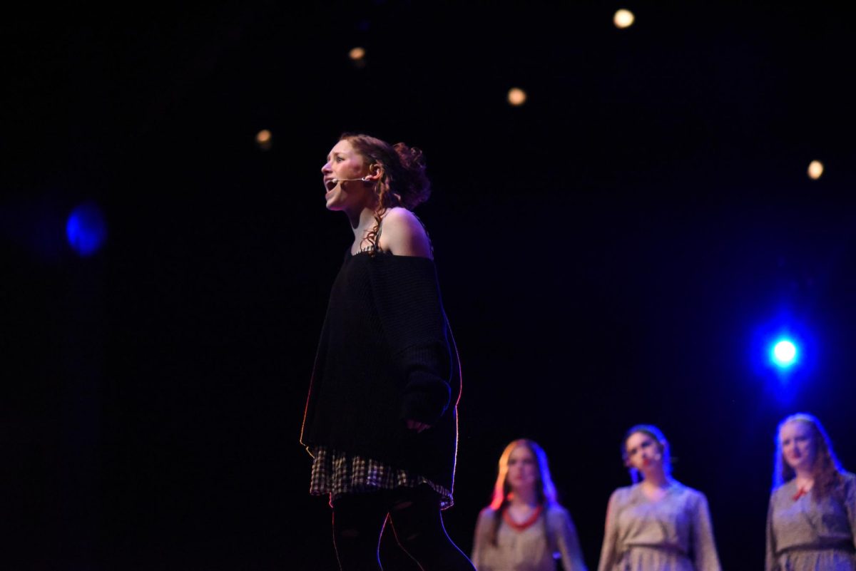 ACHING HEART. After the Fates introduce "When the Chips are Down," Eurydice (Maddie Pierce) sings out that her heart is aching in suspense because of her impending decision. 