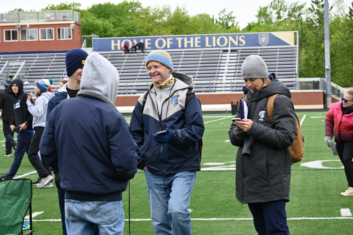 COACHES. Coach Donelly, Arey and Tepp chat amongst themselves while wearing many layers in the cold weather.