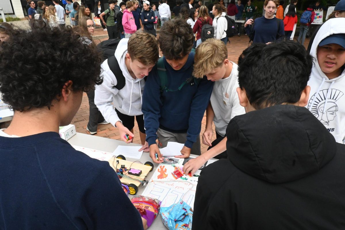 NEW EXPERIENCES. Freshman Ronan O'Connell, Zakariya Chaudhary, and Seamus Sullivan gather at a table and collect candy.