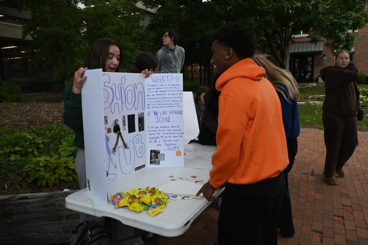 LURING THEM IN. Senior Maeve Duncan, leader of Fashion Club, pitches her club to senior Bokii Mullataa with her poster.