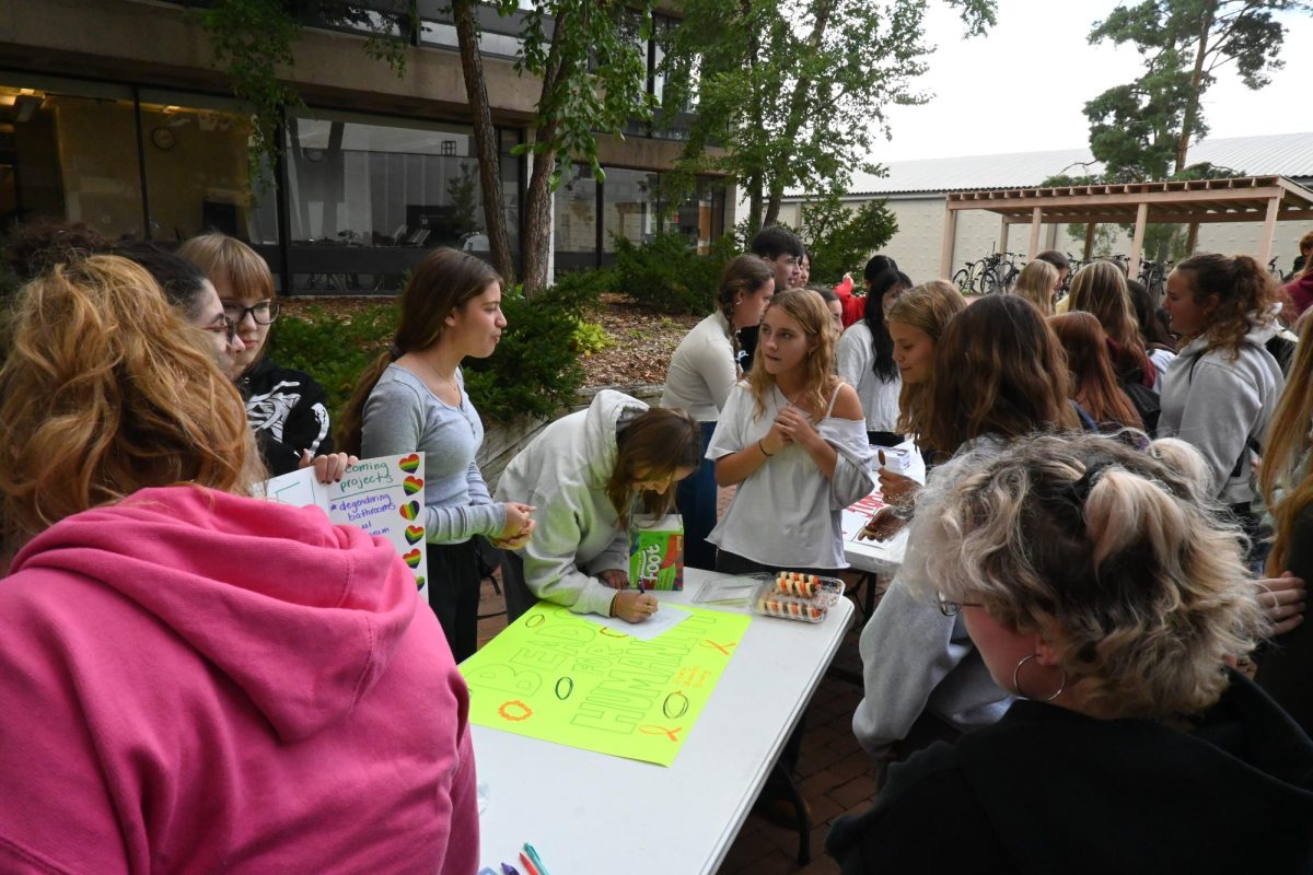 TABLE TALK. Students discuss around the Beads For Humanity table.