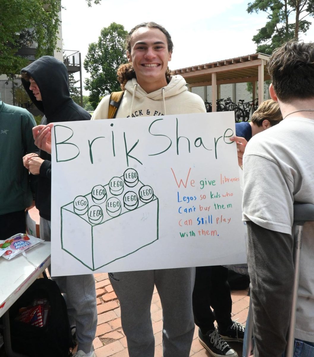 JOIN HERE. Junior Langston Thompson, leader of the BrikShare club, waves his poster to lure in nearby students.