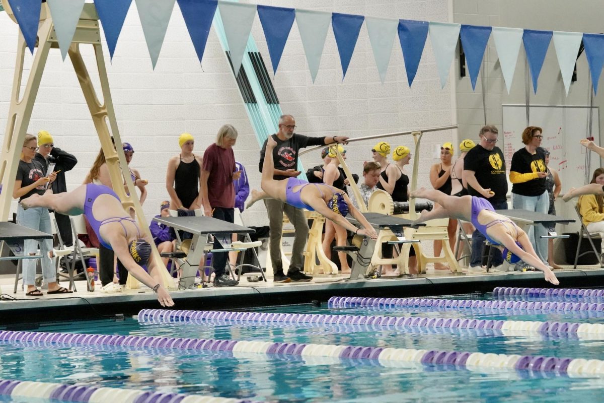 IN A LINE. Three Sparks swimmers dive in their streamline position in a line.