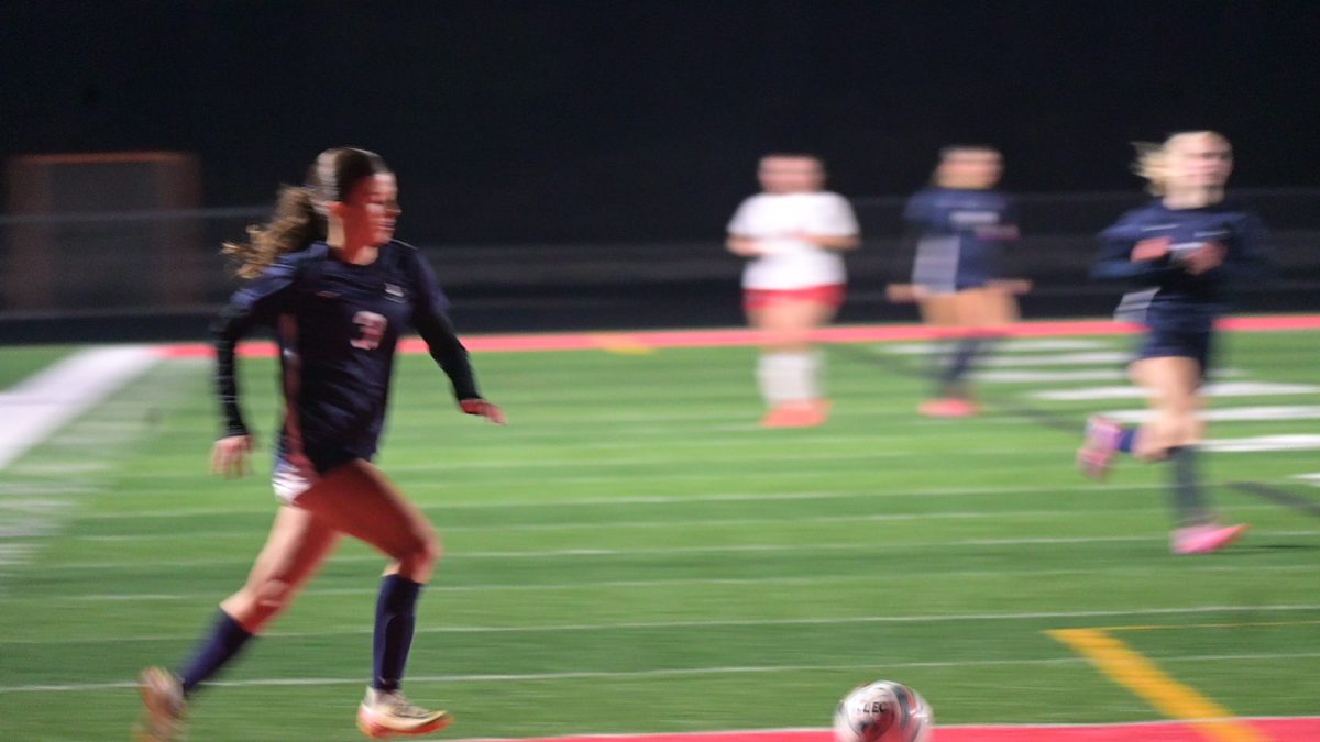 PASSING. Freshman Phoebe Gottlieb runs down the field, dribbling the ball towards the goa, and passing between herself and other teammates.