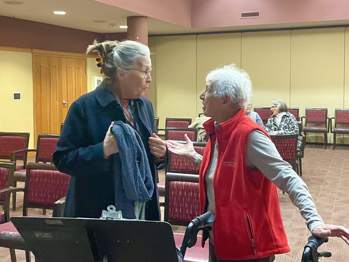 EXCITMENT. Middle School Choir teacher Mrs. Rylander speaks with the residents at Carondelet Village. Rylander helped with the choirs in September while Kraack was on paternity leave. Residents filled slowly into the room full of seats, a piano, and a small stage. "Music is an art form that most people have experience with and can understand, even if they don't know the specific songs being sung. It's an easy thing to come and enjoy for 30 minutes and leave feeling good about your day."