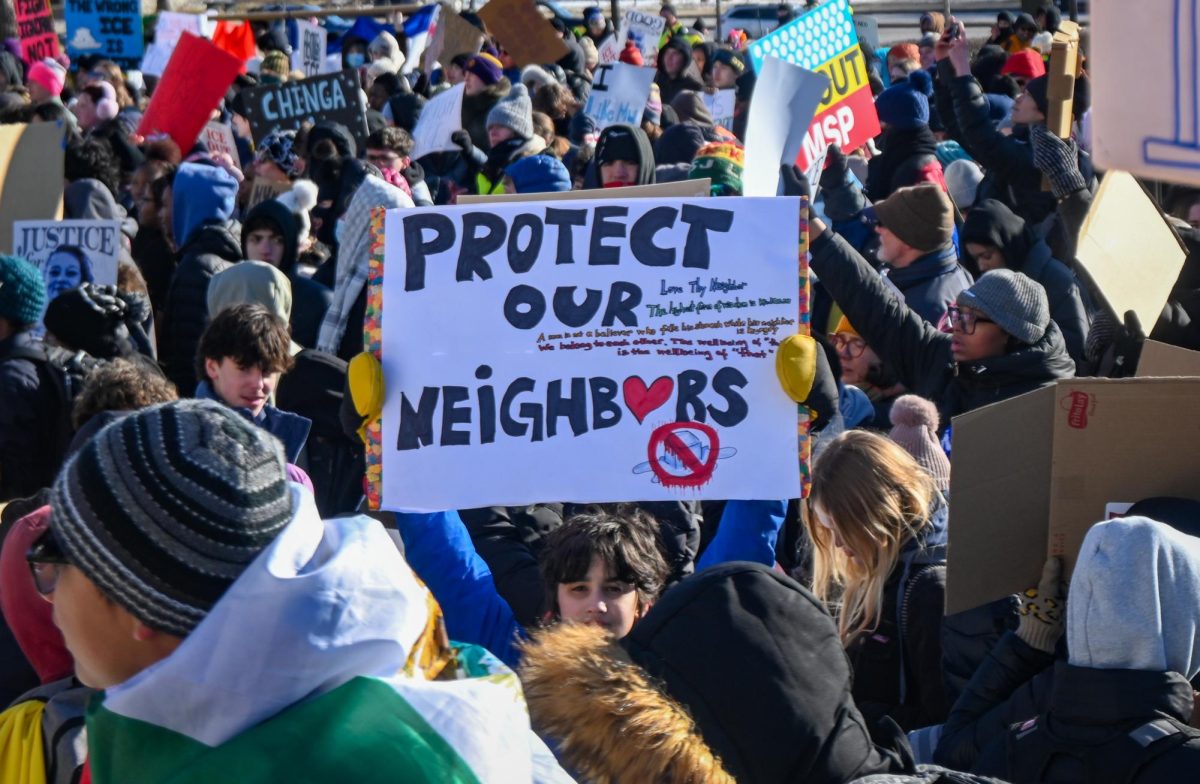 YOUNG VOICE. A student protester holds a sign saying "Protect our neighbors" above the crowd.